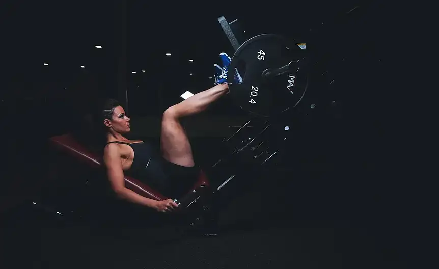 Osoba wykonująca ćwiczenia siłowe na maszynach i z wolnymi ciężarami